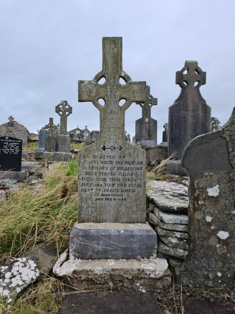 Many Celtic cross headstone. One in the foreground reads: Erected by John Lynch, Doonogan, in memory of his loving wife Maria Alias O'Groman who died 8th May 1930. May her soul rest in peace. Amen. John Lynch. Died Dec 6 1946