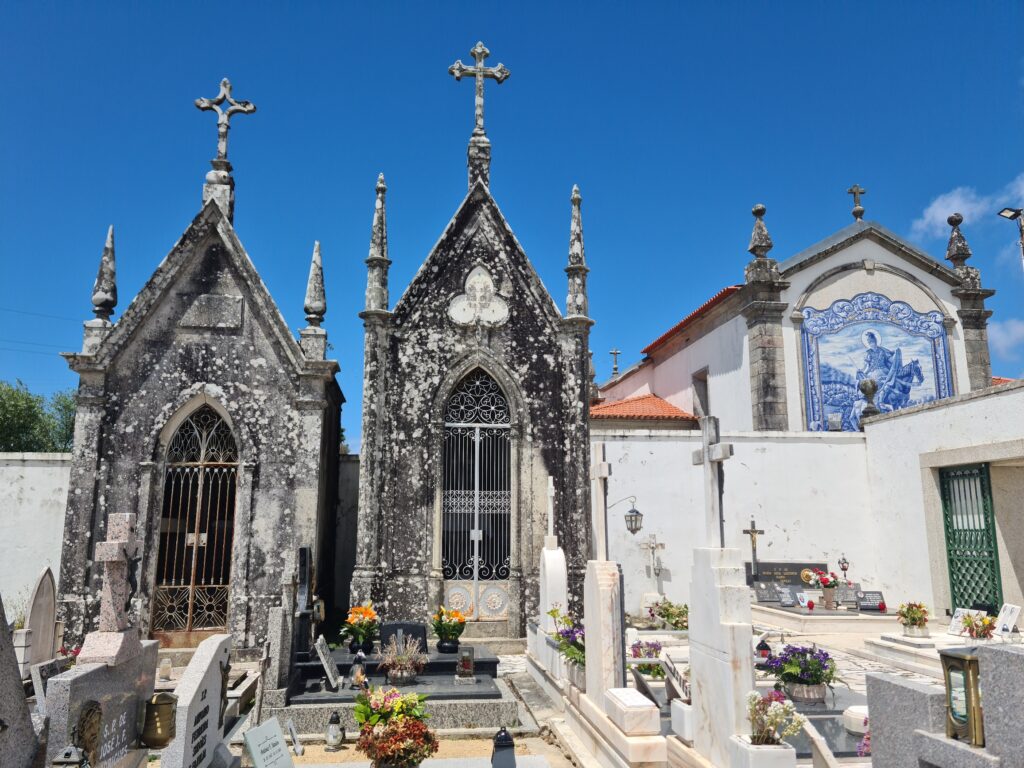 Photo of two stone mausoleums in a cemetery with a partial image of a church in the background
